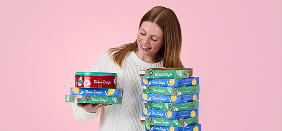 person smiling holding tart boxes and christmas cake for fundraising