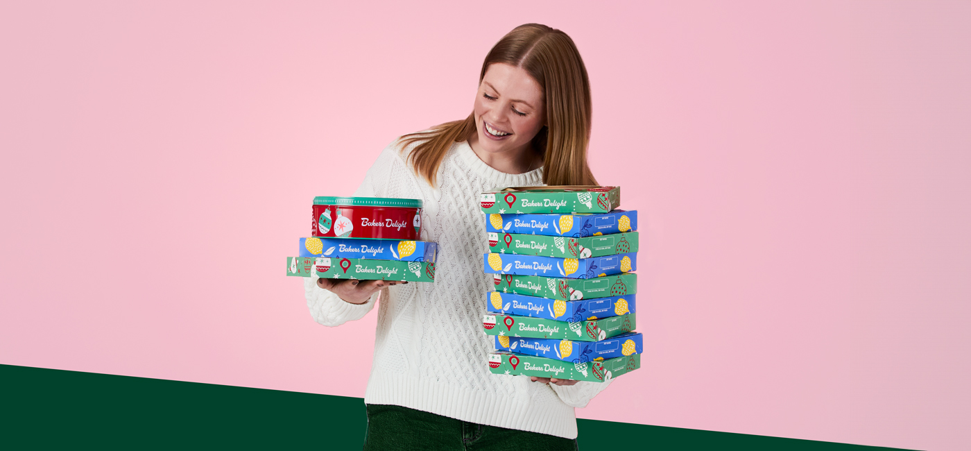 person smiling holding tart boxes and christmas cake for fundraising